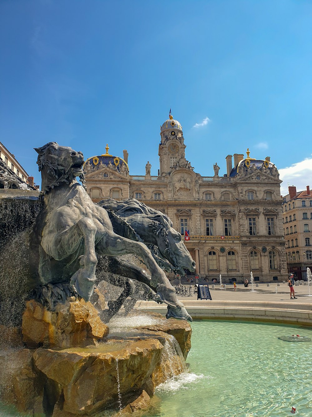 Graue Pferdestatue in der Nähe eines braunen Betongebäudes unter blauem Himmel tagsüber