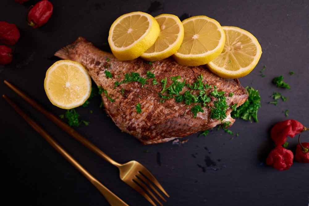 sliced lemon beside stainless steel fork on black wooden table