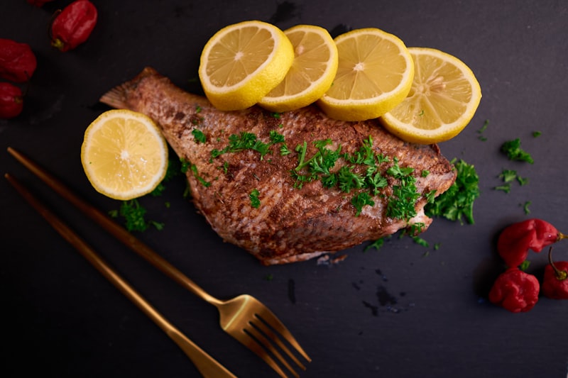 Whole pan fried fish with lemon slices and fresh parsley