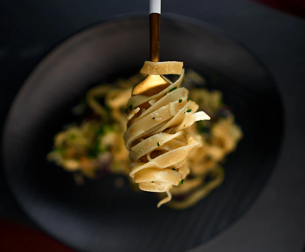 Handmade pasta plated on a black ceramic plate