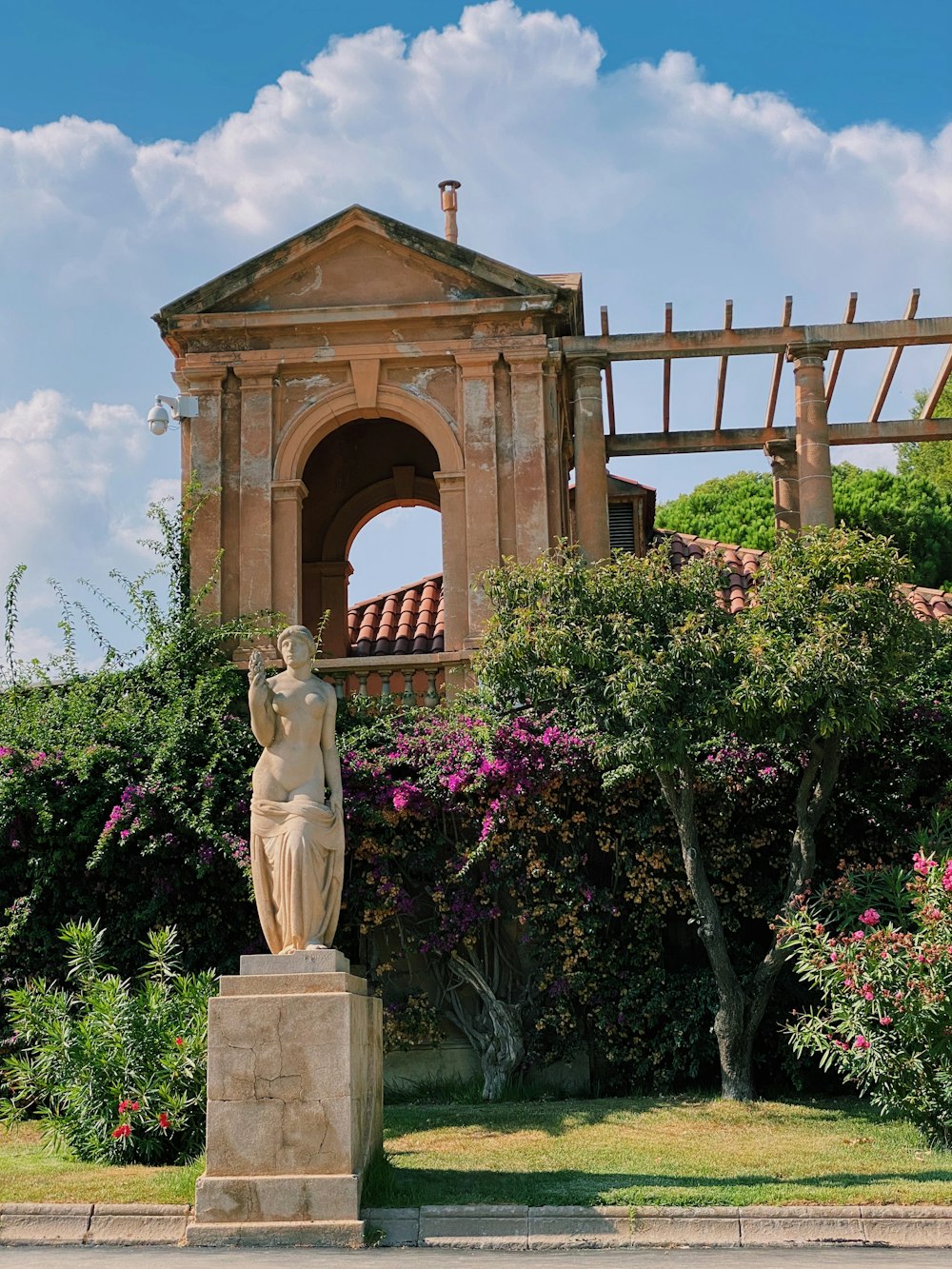 brown concrete statue near pink flowers during daytime