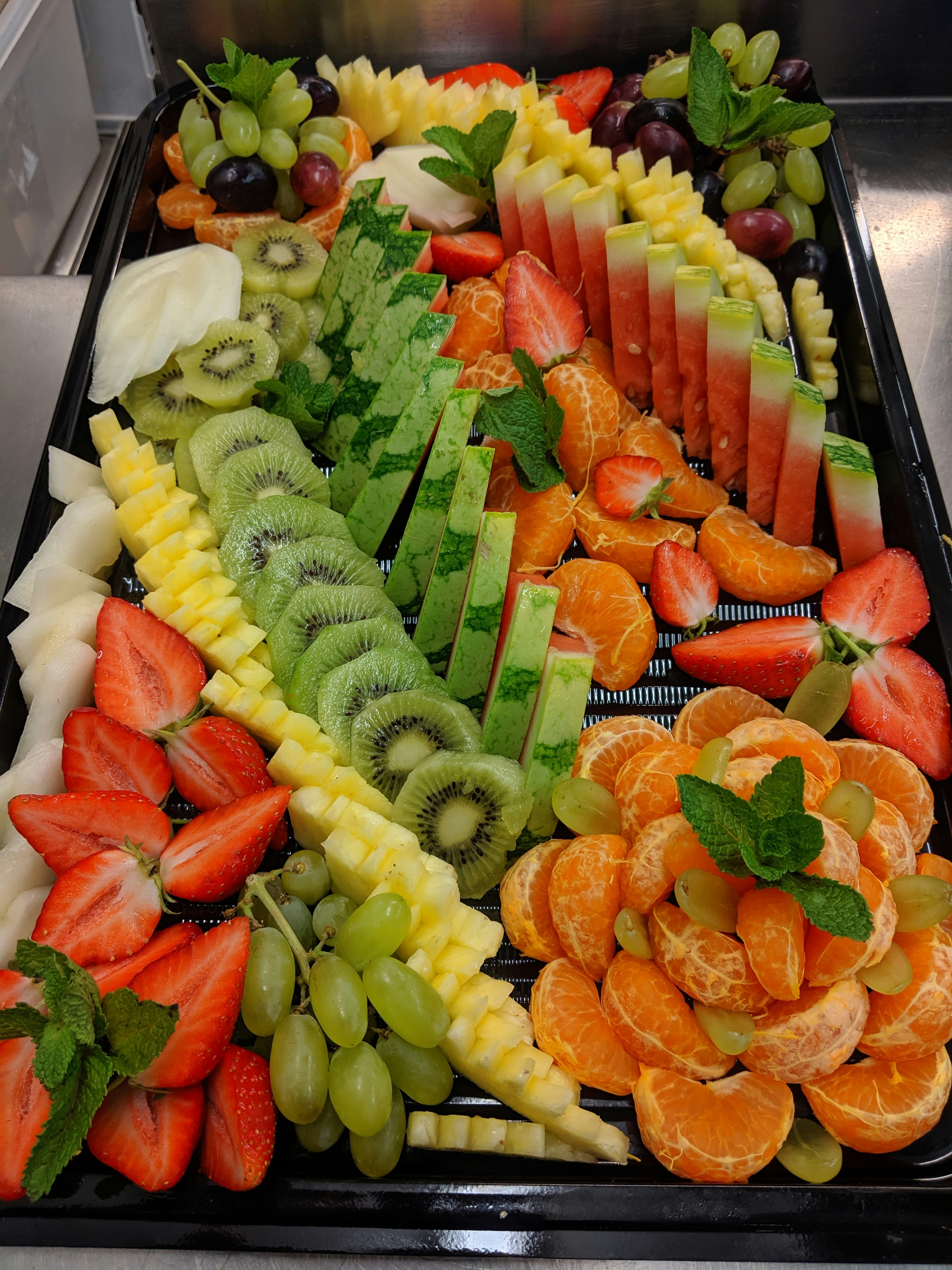 Colorful fresh fruit platter with sliced mango, strawberry, kiwi and pineapple