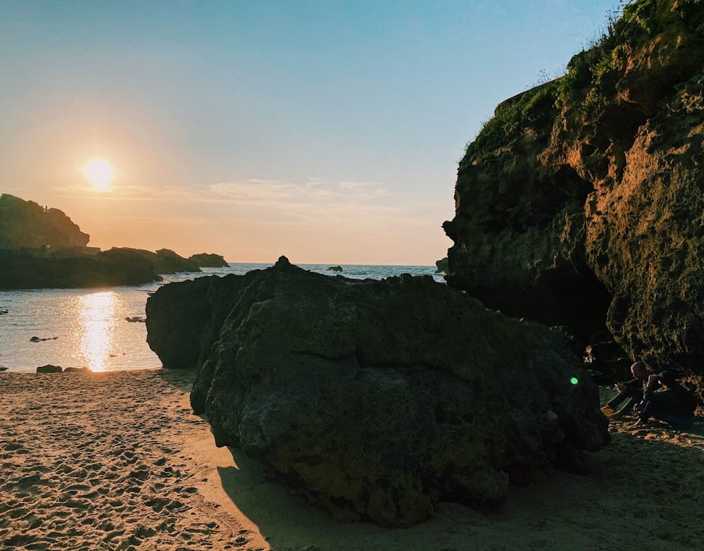 black rock formation near body of water during daytime