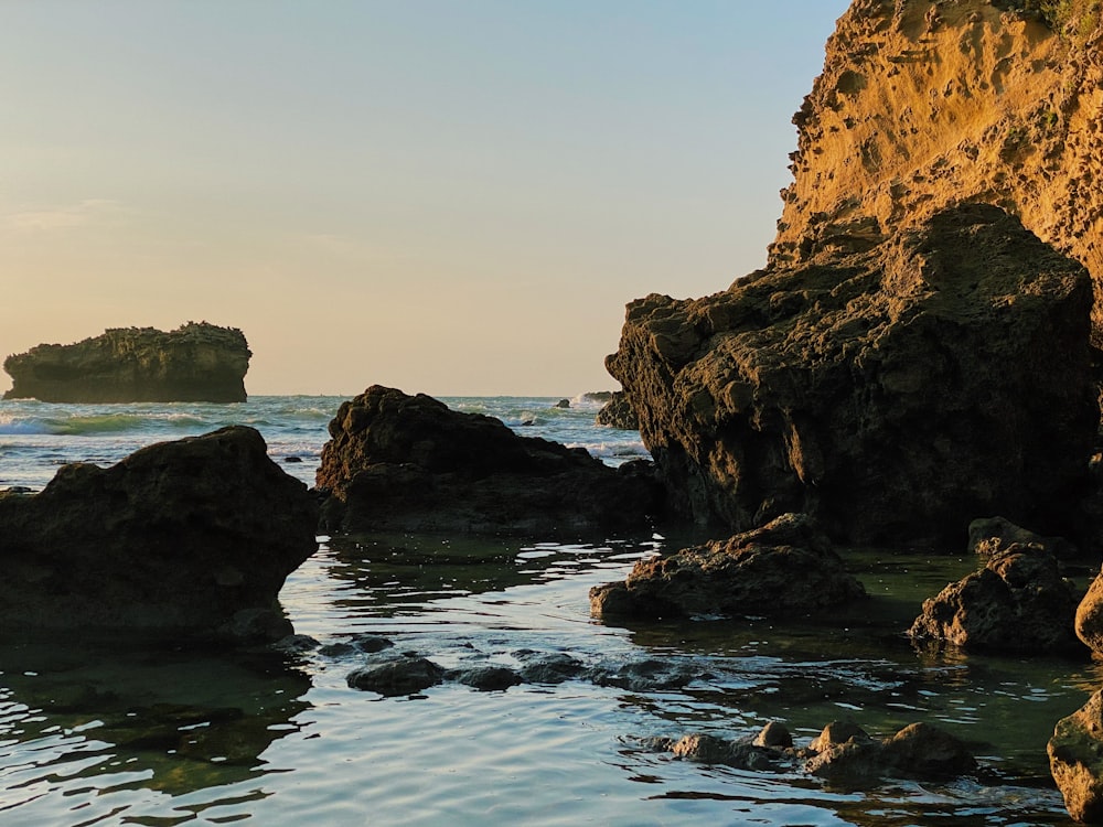 brown rock formation on body of water during daytime