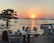 A smiling couple enjoying a sunset dinner on the seaside terrace of a tropical restaurant.