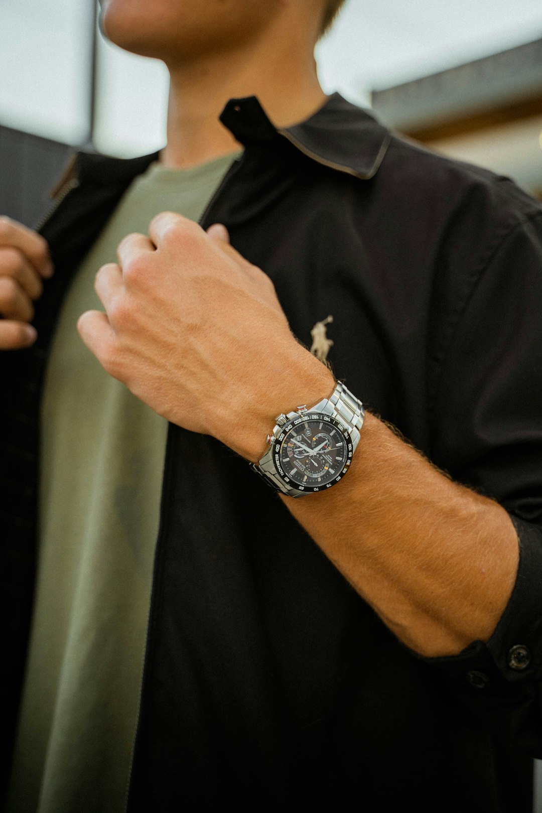 person in black jacket wearing silver round analog watch