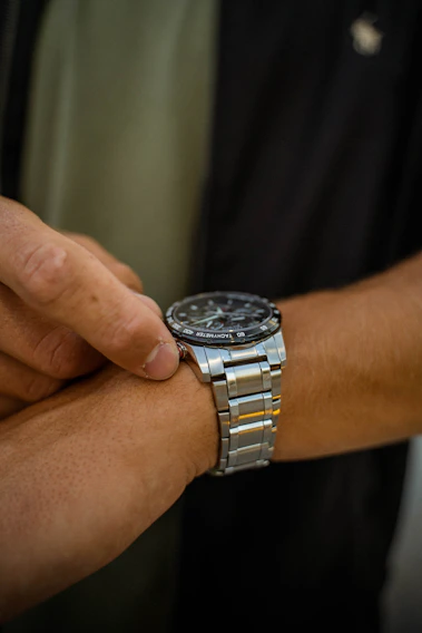 A stylish lady wearing a sleek silver watch from lunavėjas, smiling as she checks the time.