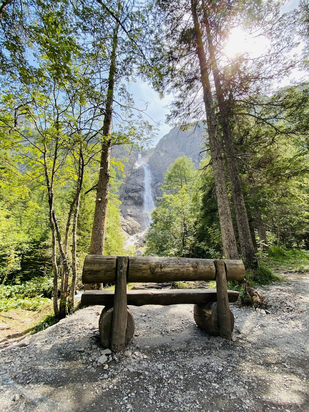 brown wooden bench on brown rock near green trees during daytime