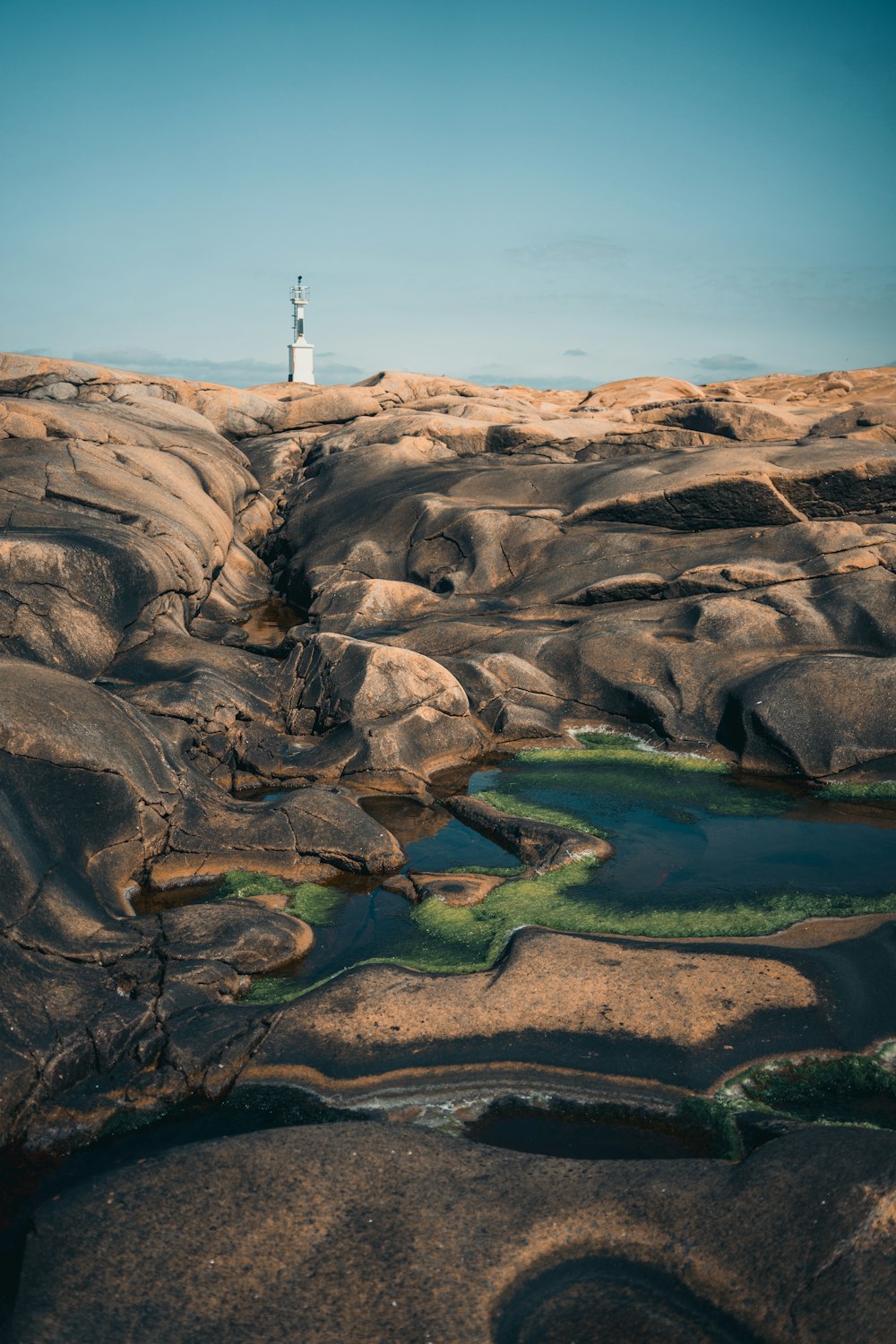 white lighthouse on brown rock formation during daytime