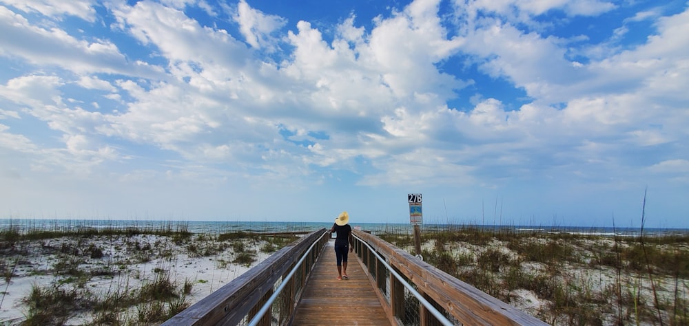 woman in black jacket walking on wooden dock during daytime