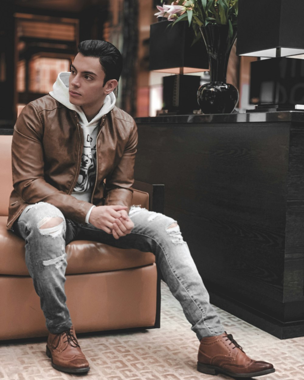man in brown leather jacket sitting on brown leather couch