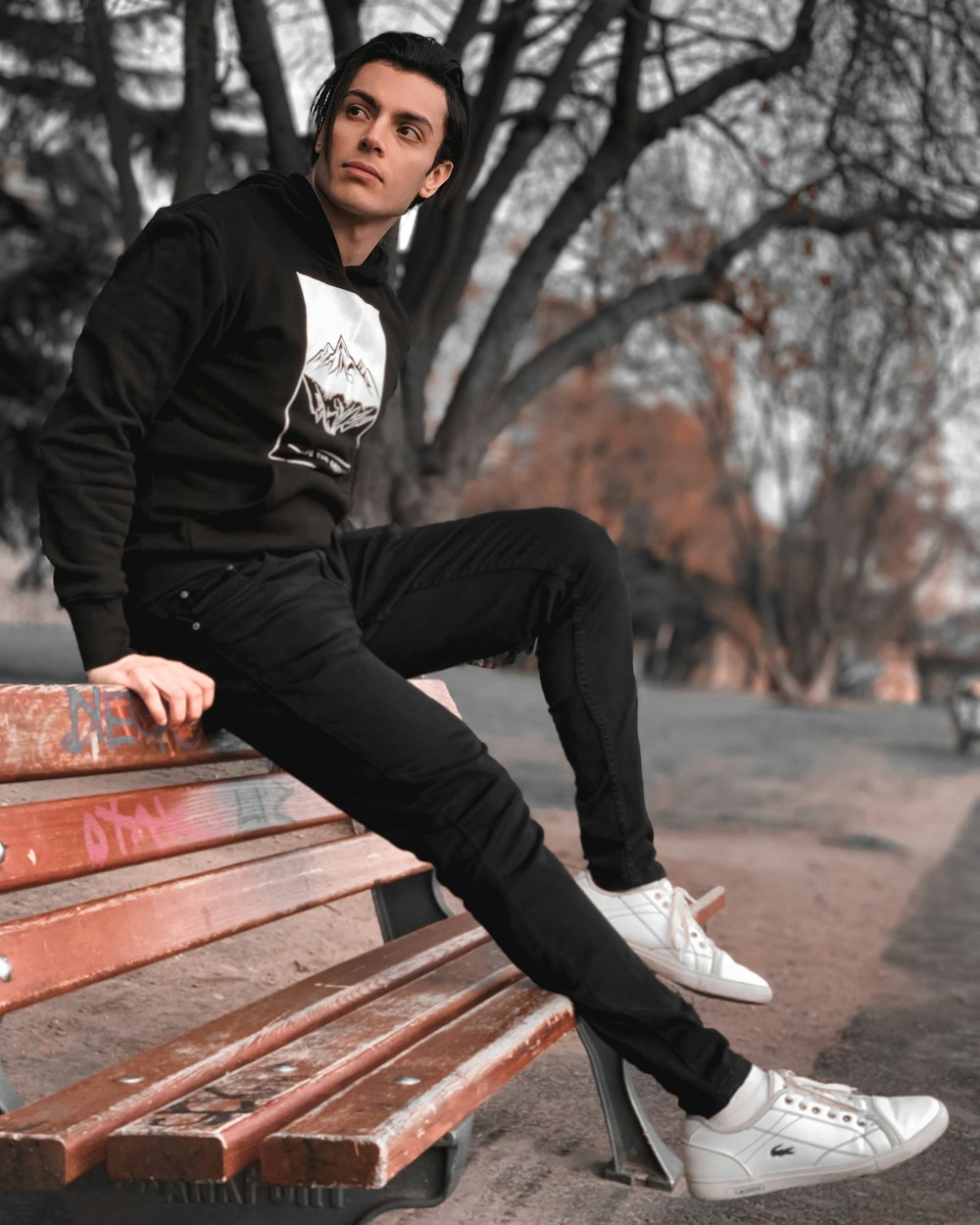man in black jacket sitting on brown wooden bench during daytime