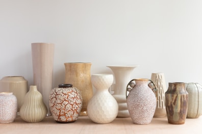 A set of ceramic vases in soft earth tones arranged on a wooden table.