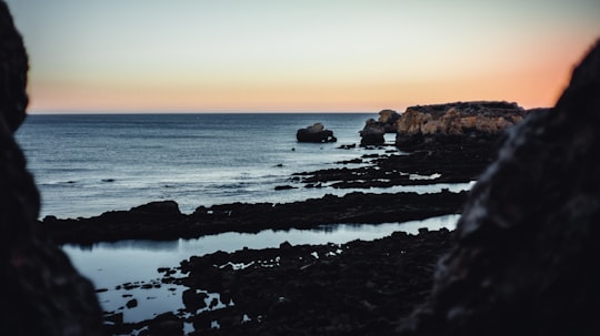 body of water near brown rock formation during sunset in Albufeira Portugal