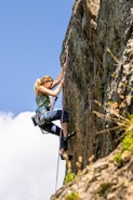 a woman climbing up the side of a mountain