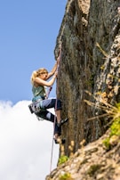 a woman climbing up the side of a mountain