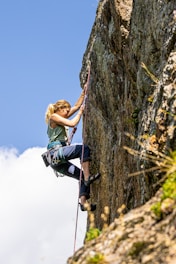 a woman climbing up the side of a mountain