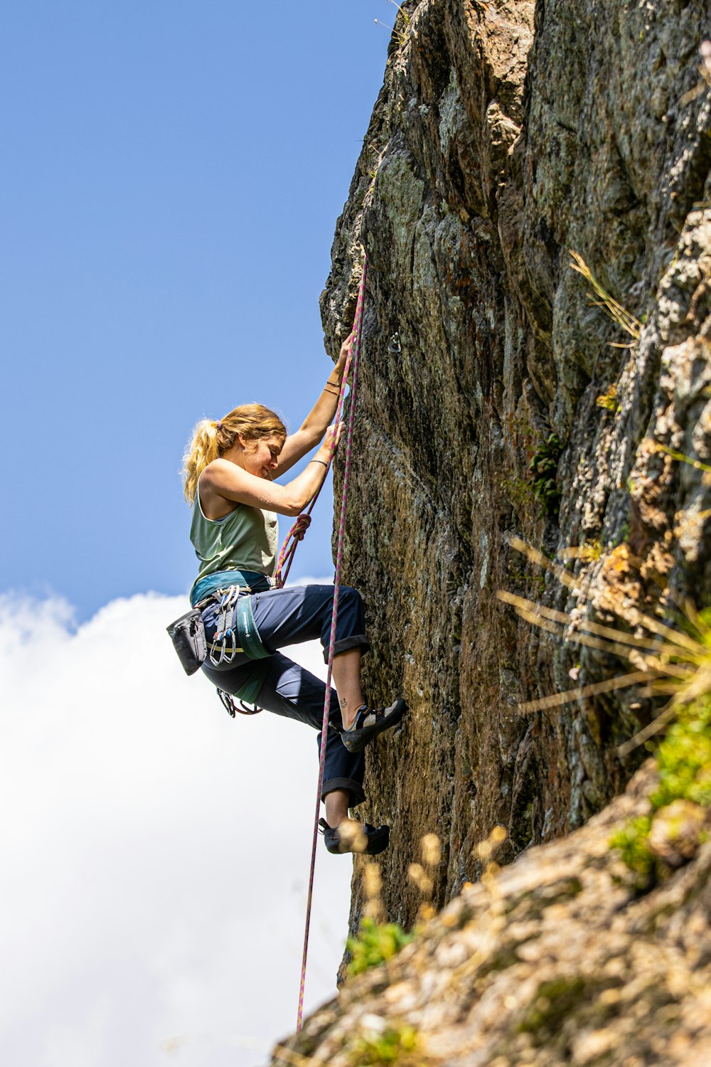 a woman climbing up the side of a mountain