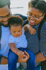 woman in black and white striped shirt carrying baby in white onesie