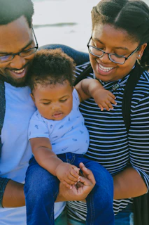 woman in black and white striped shirt carrying baby in white onesie