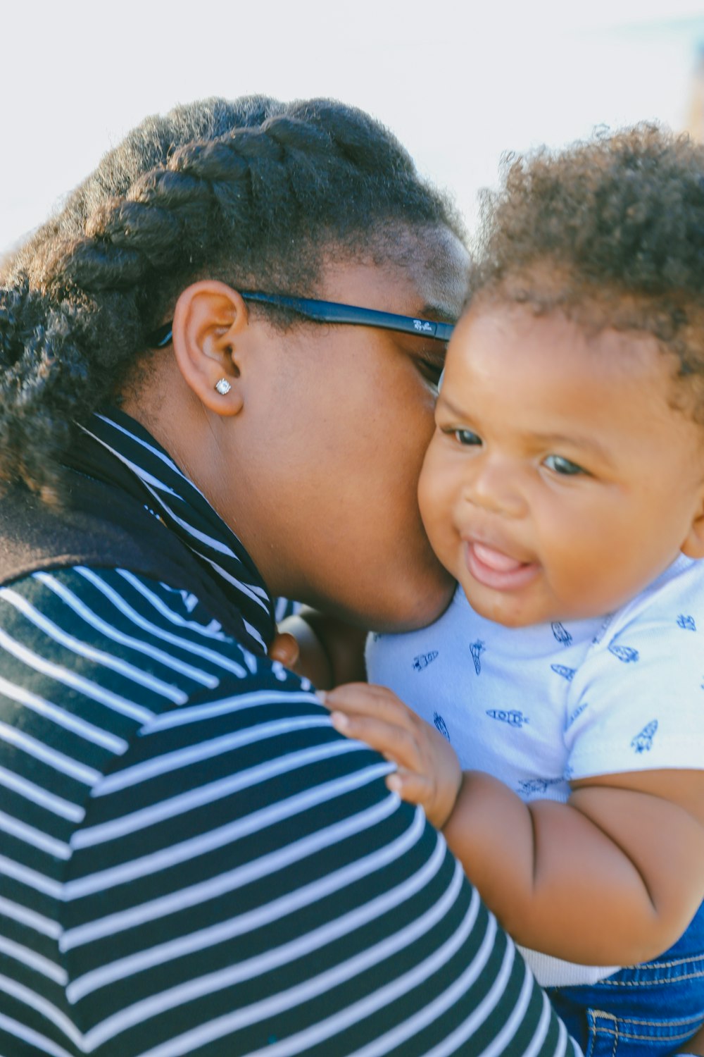 woman in black and white striped shirt carrying baby in white onesie