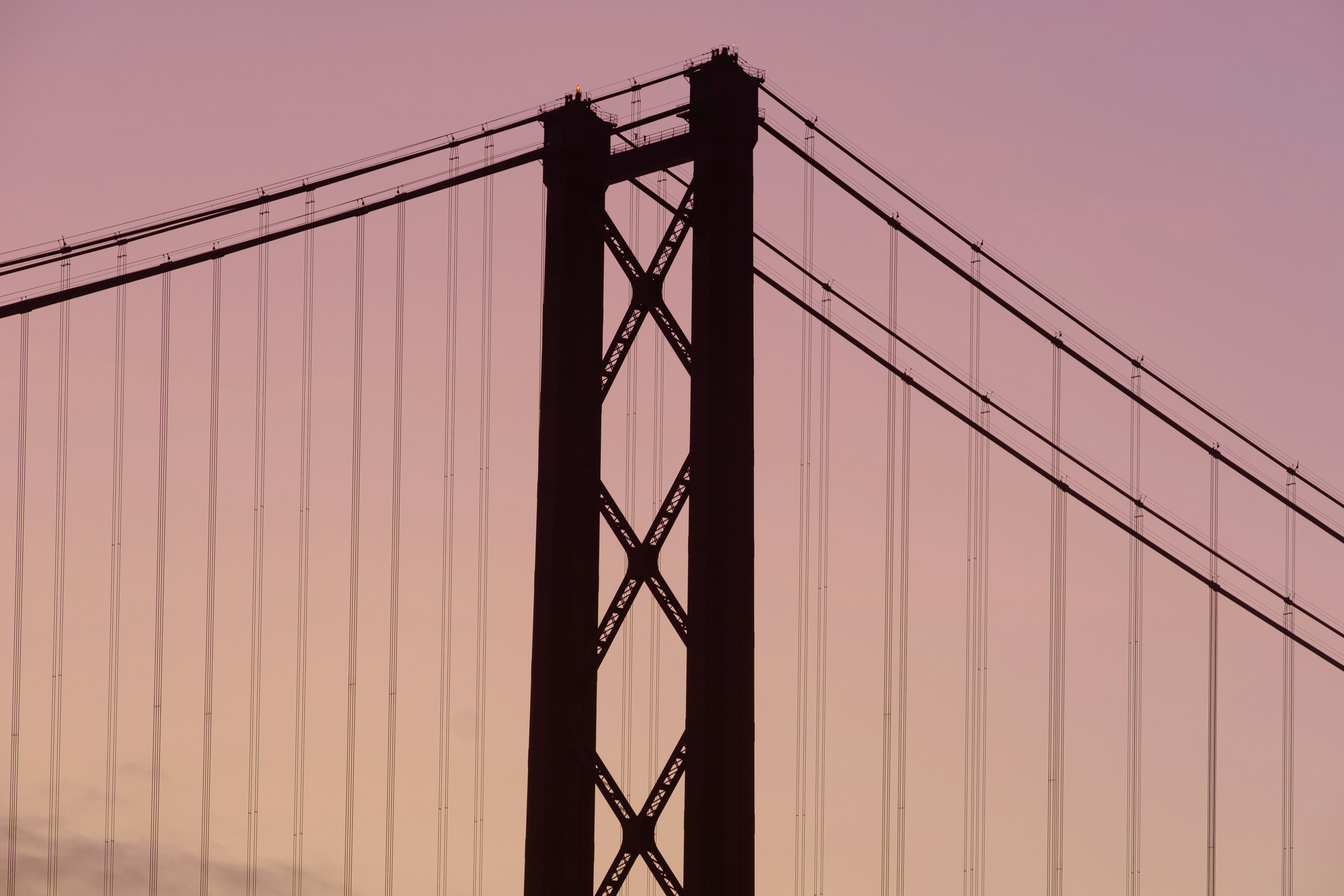 Ponte 25 de Abril (25 de Abril Bridge) during sunrise with orange hue sky