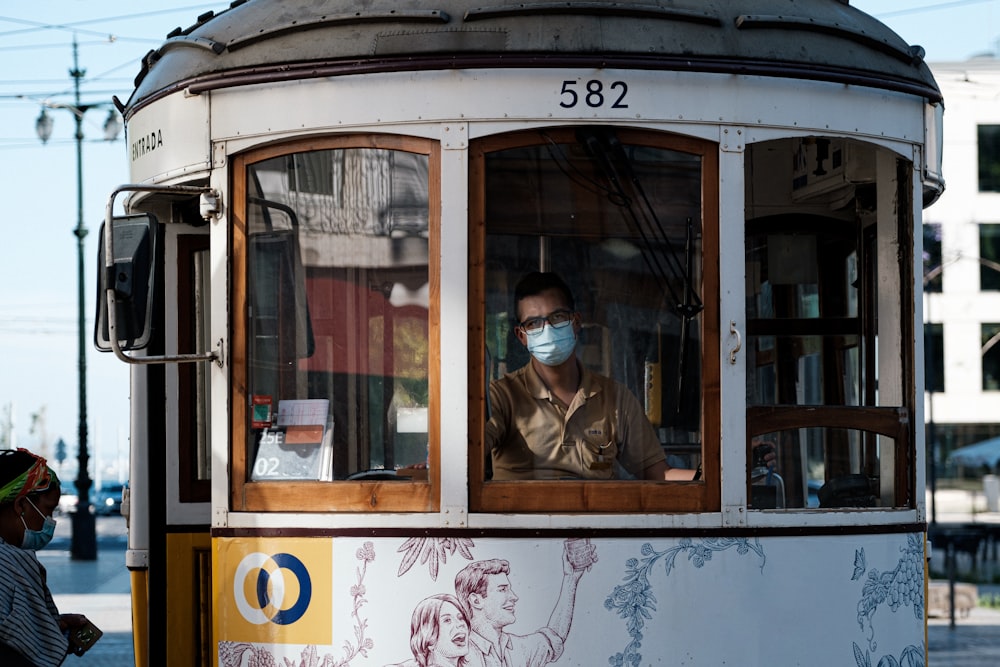 woman in brown jacket riding on white and blue train