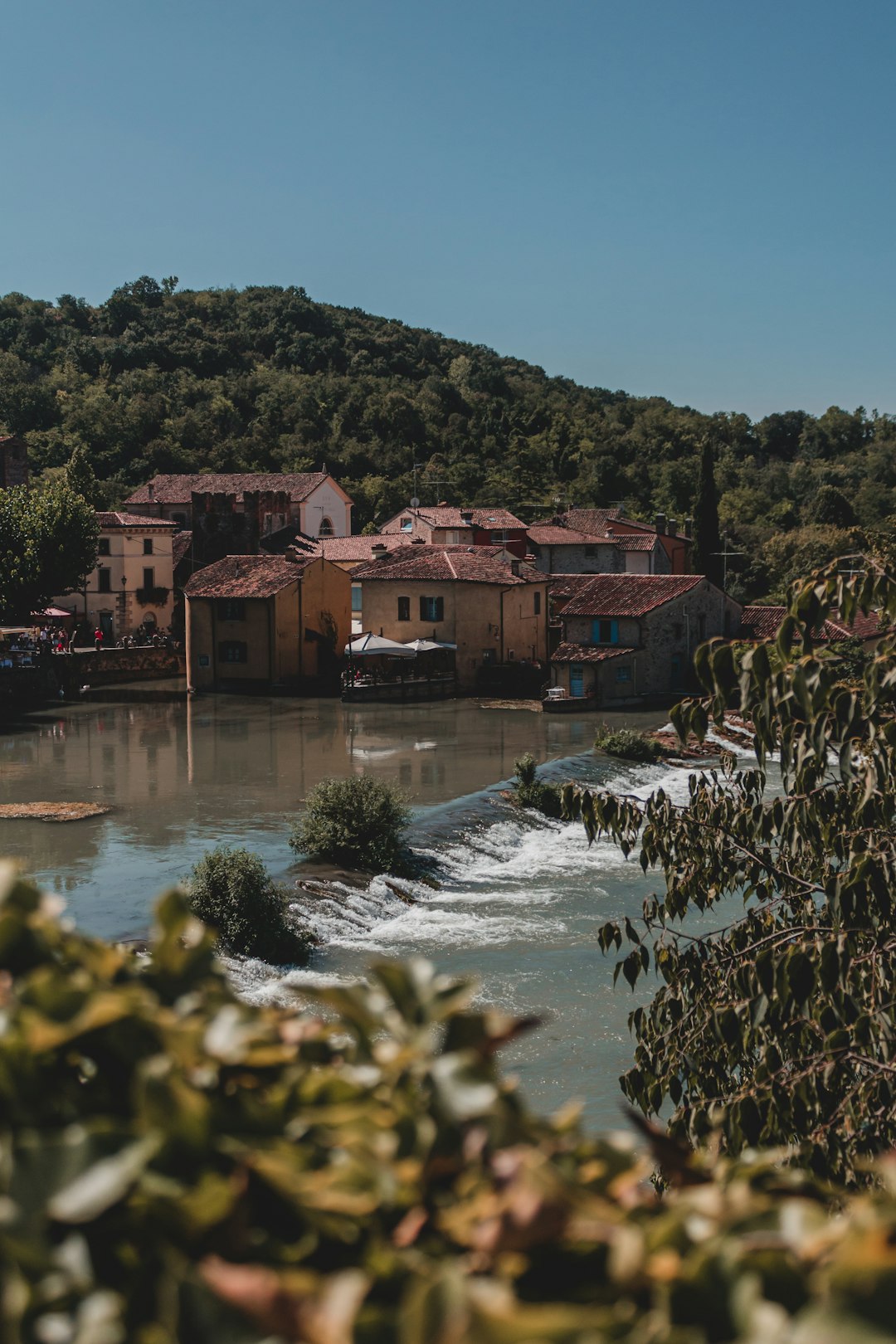 brown and white concrete house near green trees and river during daytime