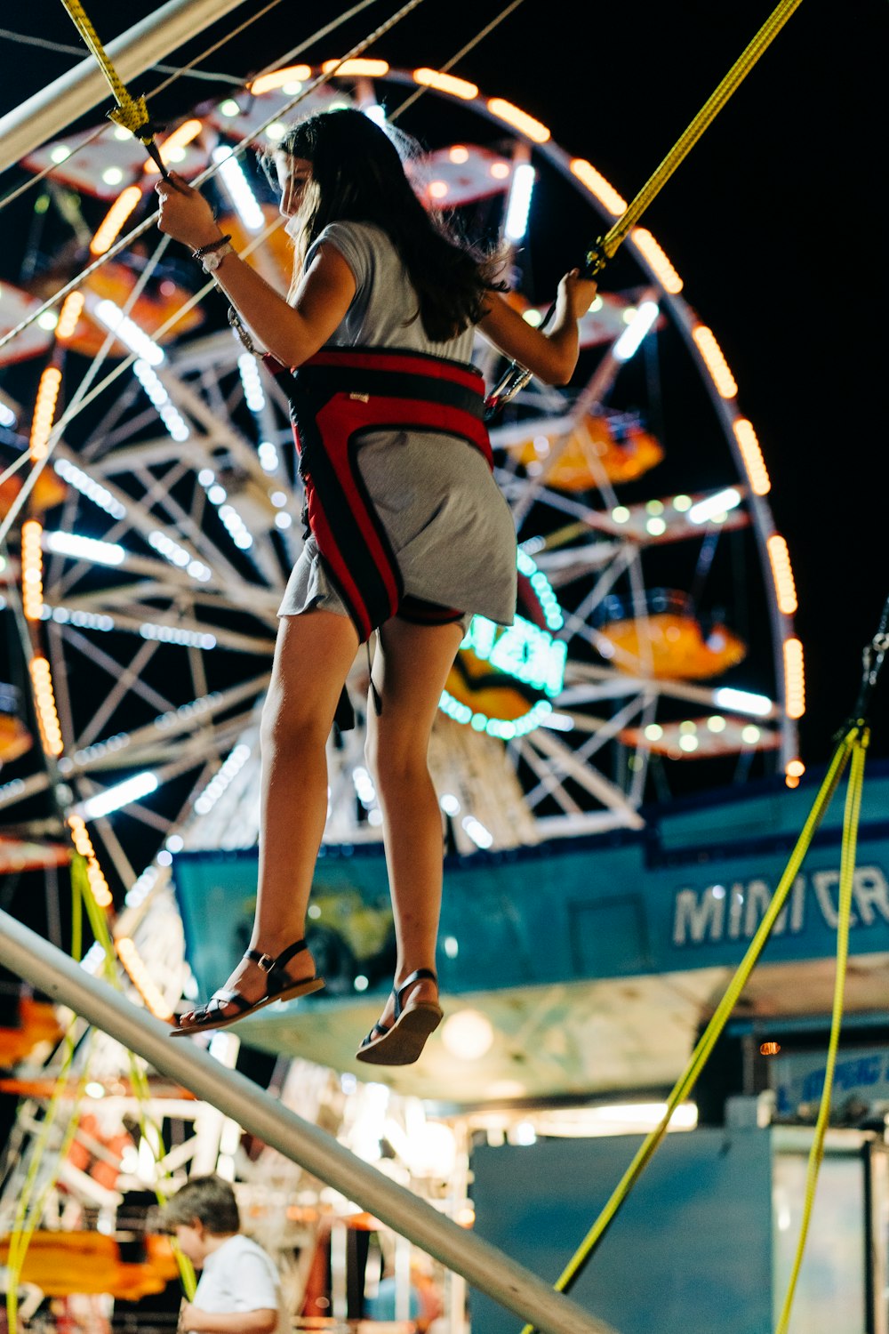 Mujer con camisa de punto roja y blanca y pantalones cortos saltando sobre una barra de metal azul