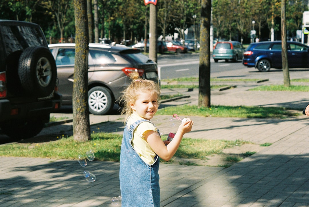 girl in white tank top and blue denim shorts standing on sidewalk during daytime