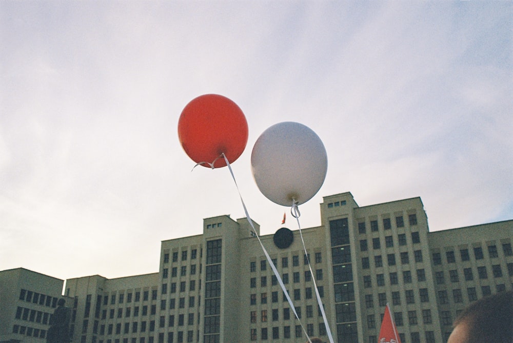 red balloon on mid air near white building during daytime