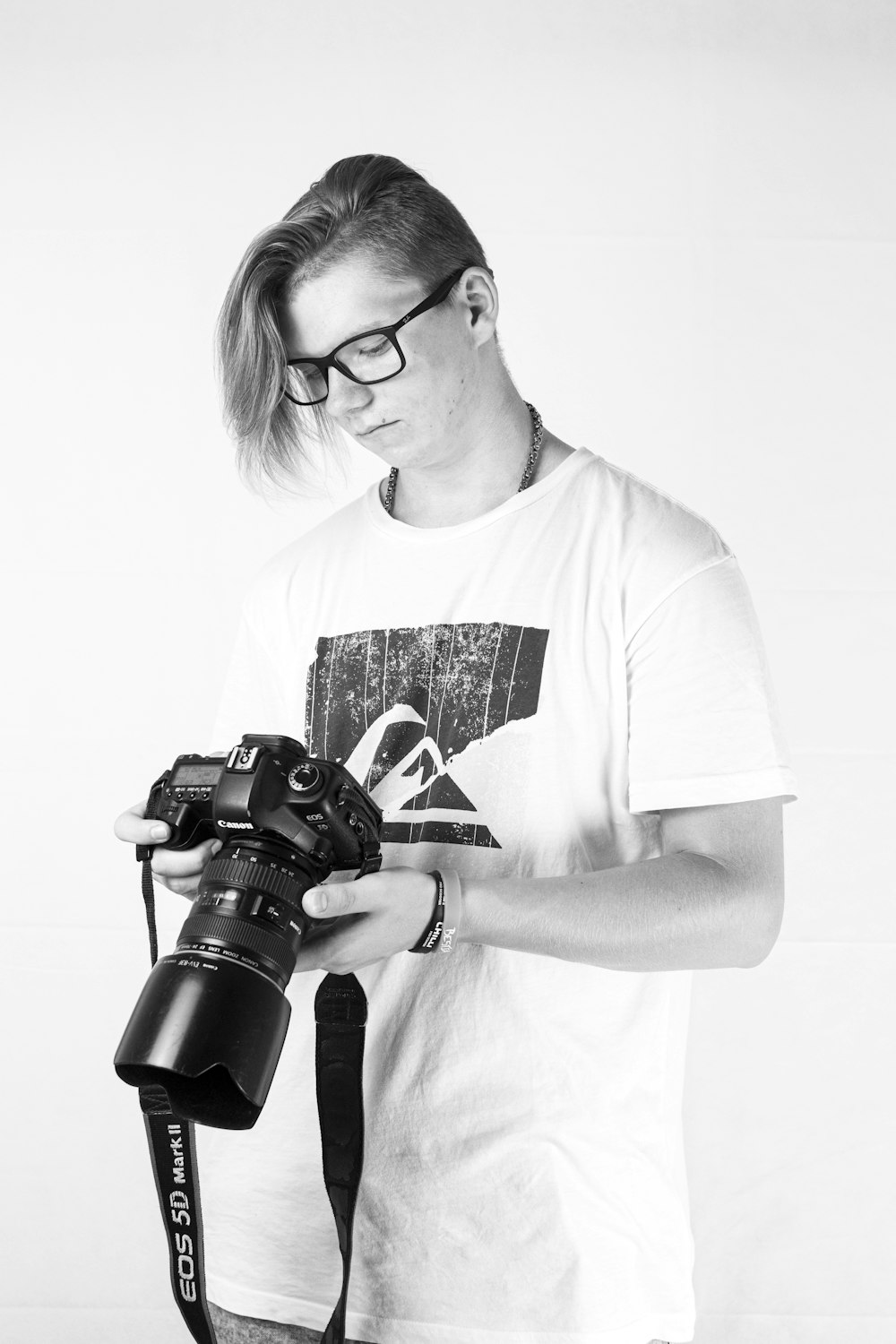 man in white crew neck t-shirt holding black dslr camera