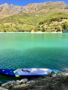 A calm turquoise lake with a paddleboarder gliding smoothly near the shore.