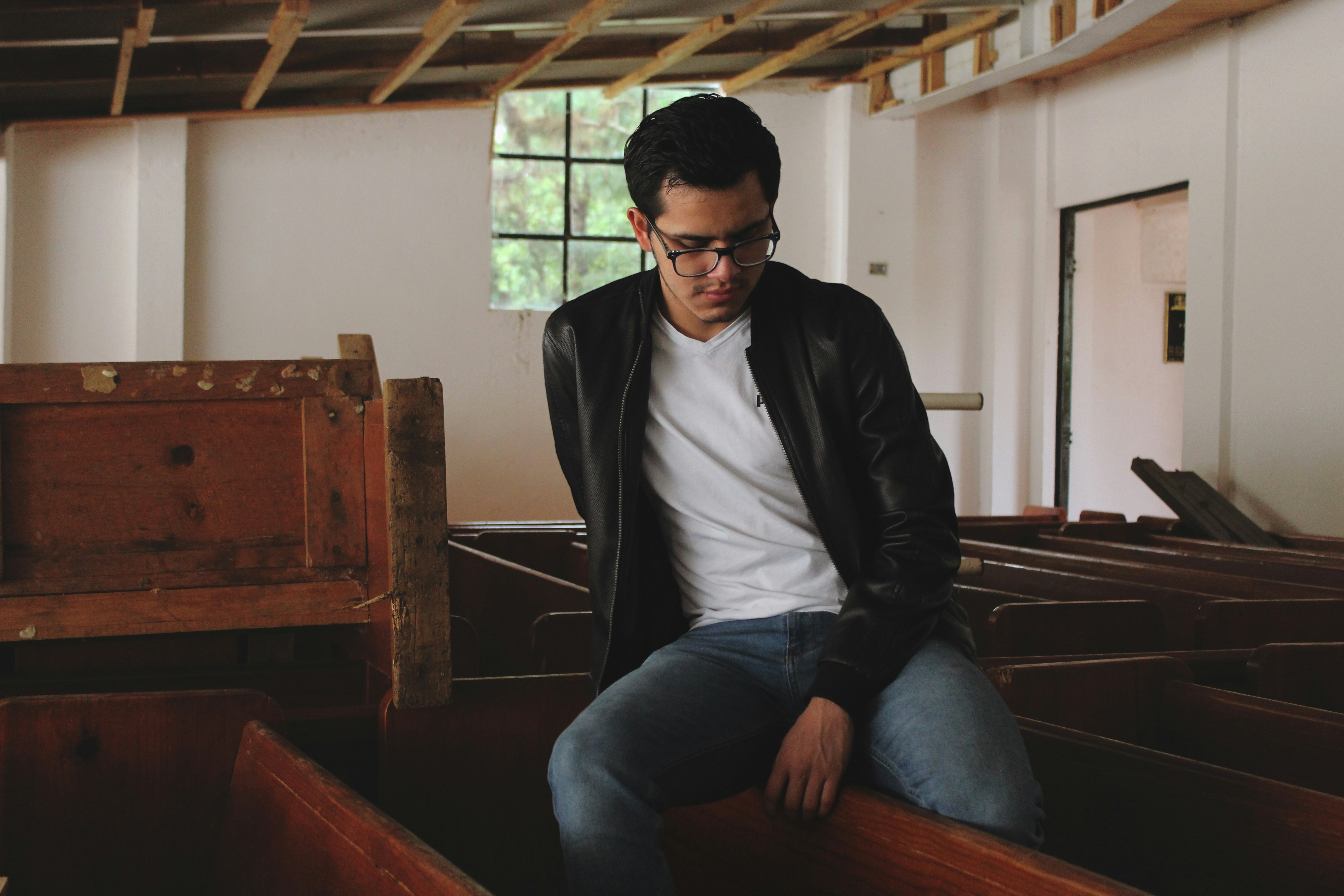 man in black leather jacket sitting on brown wooden bench pueblo revival teams background