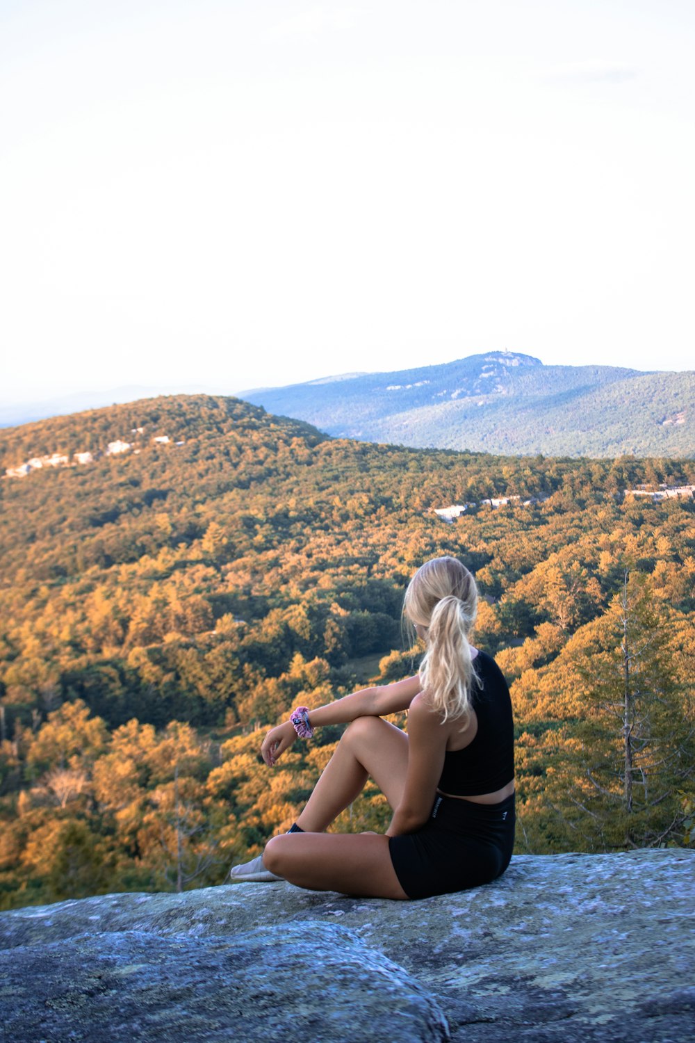 woman in black t-shirt sitting on brown rock during daytime