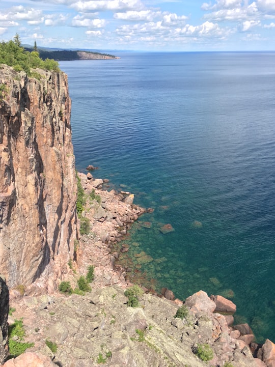 brown rocky mountain beside blue sea during daytime in Tettegouche State Park United States