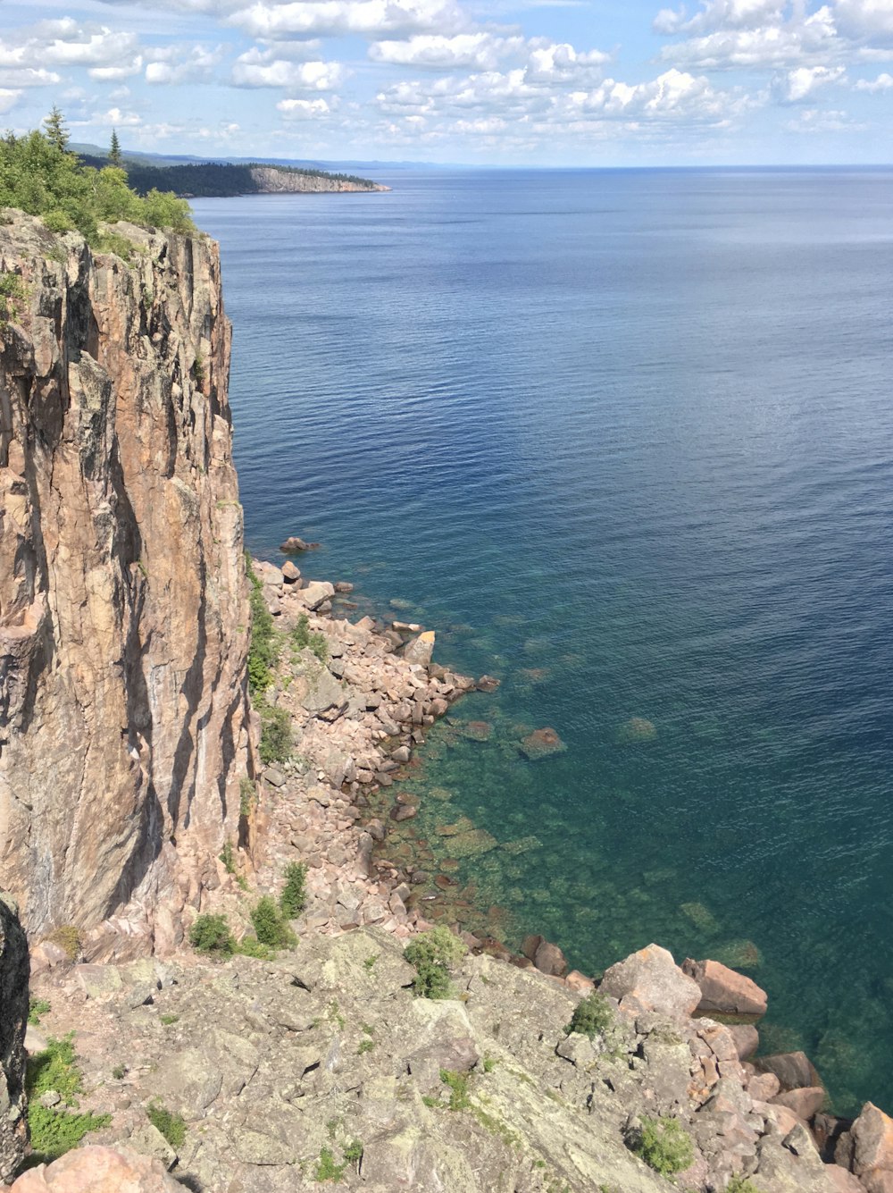 brown rocky mountain beside blue sea during daytime