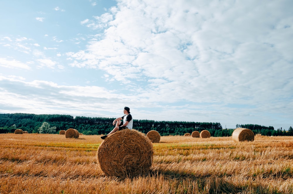 man in white shirt standing on brown grass field under white clouds and blue sky during