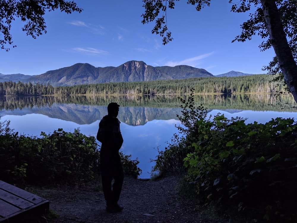 woman in black jacket standing near lake during daytime