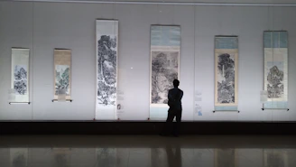 A user browsing and selecting traditional Chinese paintings on a digital tablet in a cozy room.