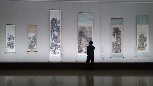 A user browsing and selecting traditional Chinese paintings on a digital tablet in a cozy room.