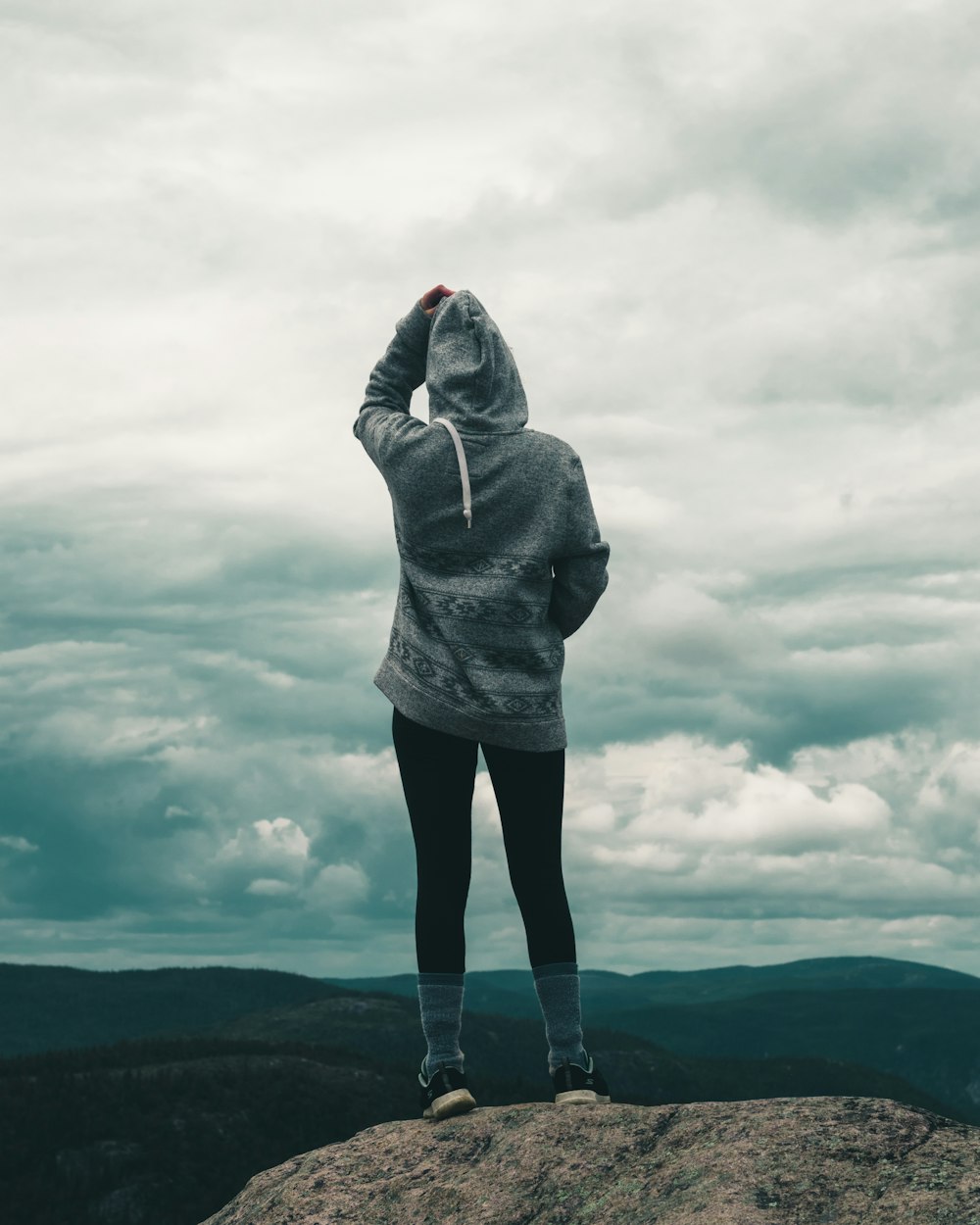 person in gray hoodie standing on gray clouds