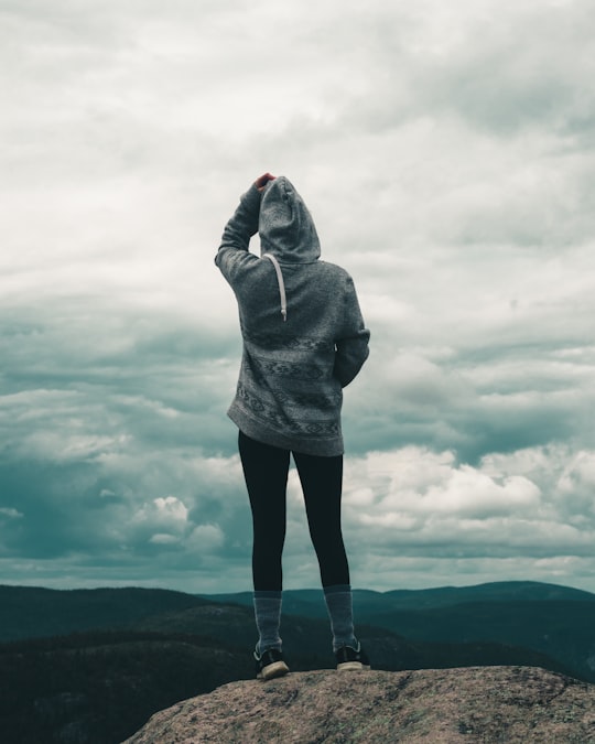 person in gray hoodie standing on gray clouds in Grands-Jardins National Park Canada