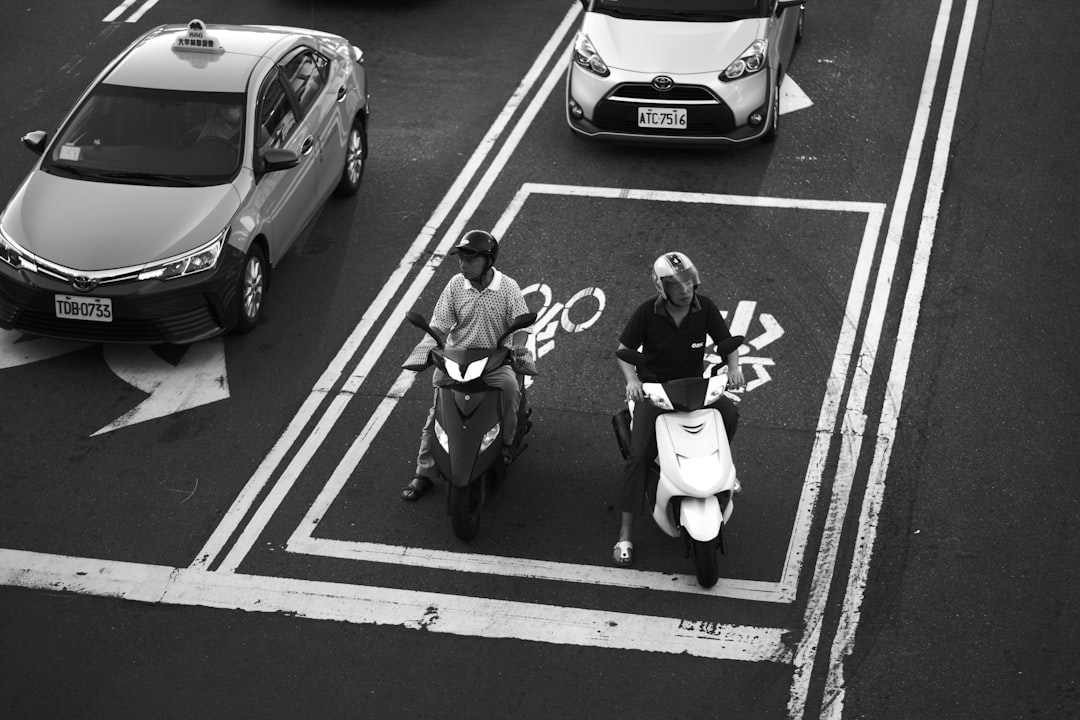 grayscale photo of 2 men sitting on the road