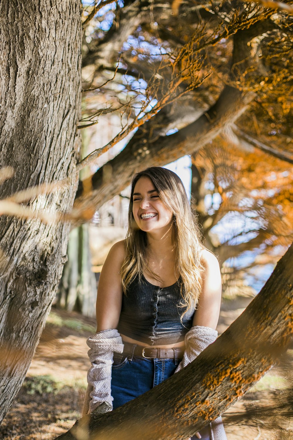 woman in black tank top sitting on tree trunk during daytime