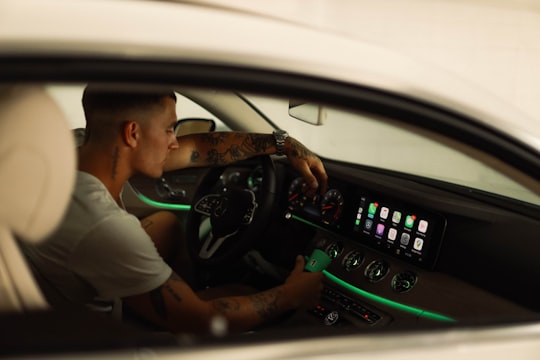 man in white polo shirt driving car in Downtown United States