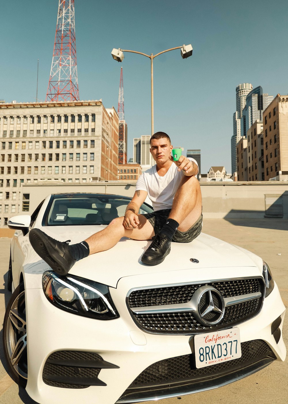 man in white t-shirt and black pants sitting on white car
