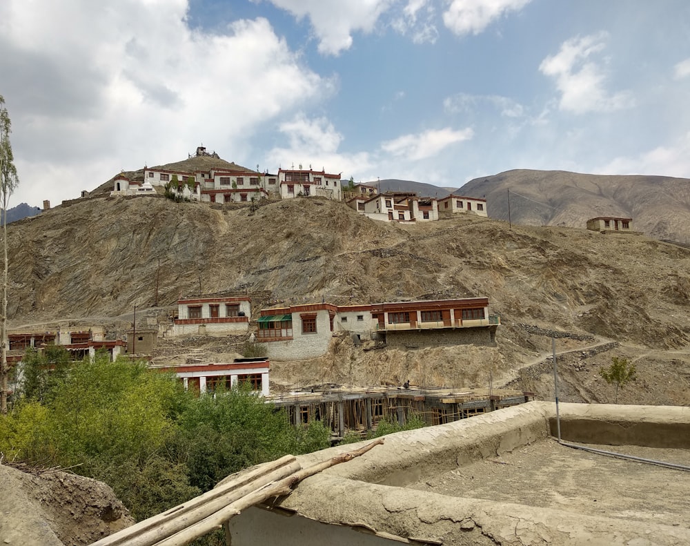 white and red concrete building near mountain under cloudy sky during daytime