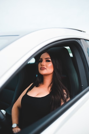 A smiling young woman behind the wheel, focused while learning to drive a car.