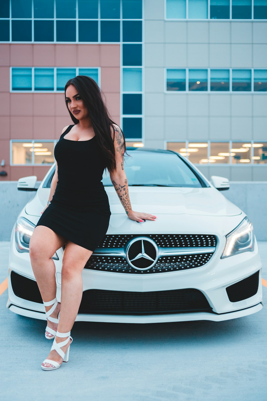 woman in black tank top and black mini skirt standing beside white mercedes benz car